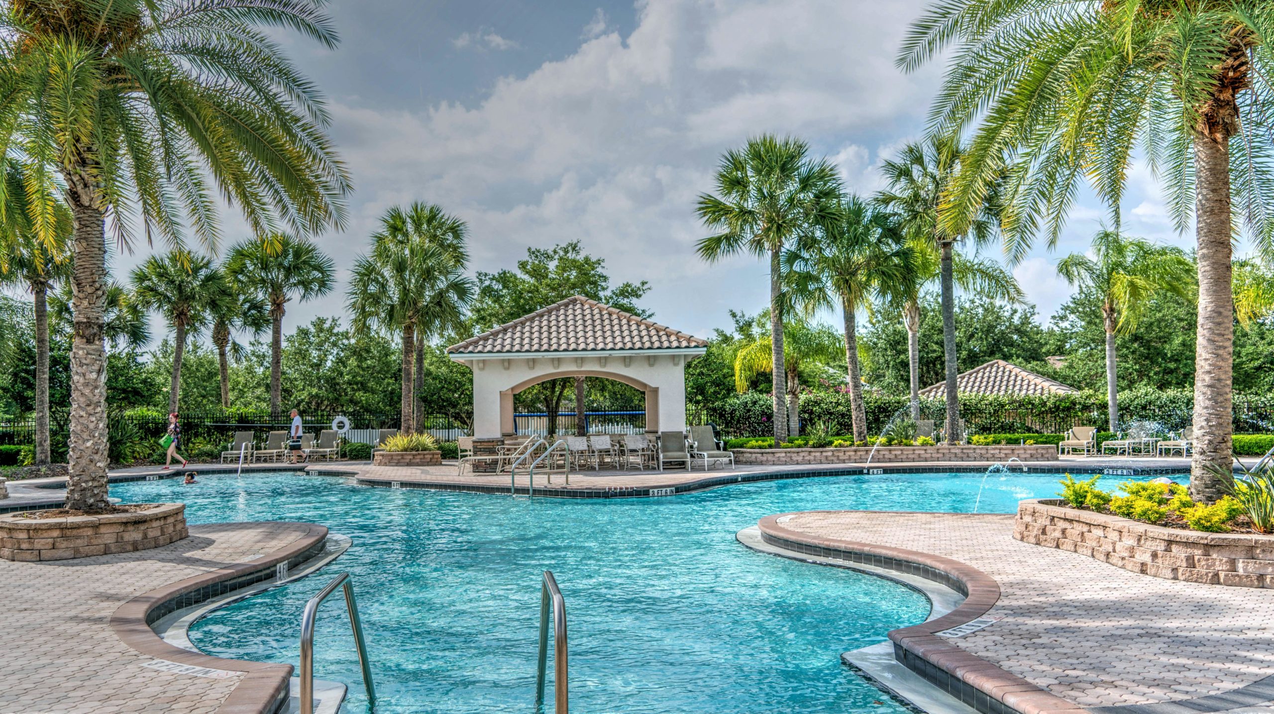 Relaxing tropical poolside scene with palm trees, gazebo, and clear blue water at a luxury resort.