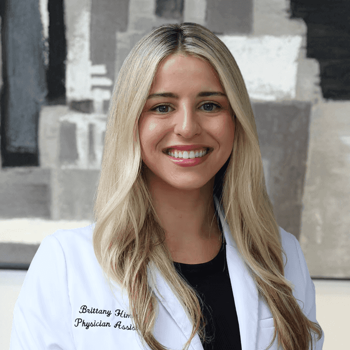 Brittany in a black top with white lab coat smiles for the camera.